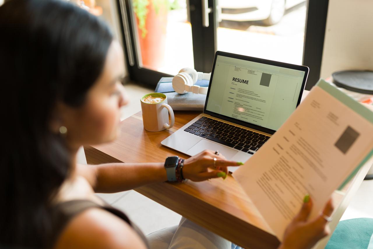 A woman reviews a resume at a desk (Adobe Stock Photo)