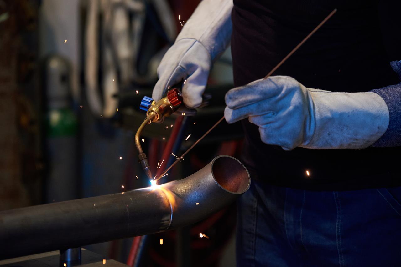 A worker welds a steel pipe at an industrial facility in Katowice, Poland. (Adobe Stock Photo)
