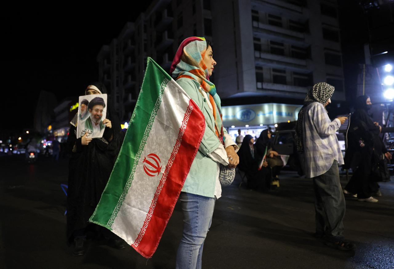Women hold Iran's national flag and photos of country's supreme leader Mojtaba Khamenei and his predecessor and late father Ali Khamenei at the Hafte Tir Square in Tehran, May 17, 2026. (AFP Photo)