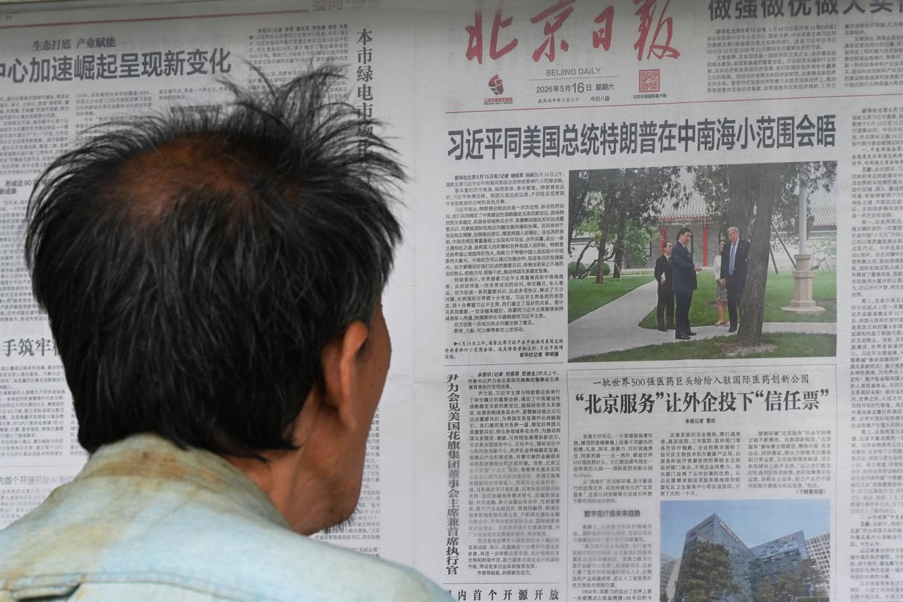 A man reads a newspaper with an article about the visit of US President Donald Trump to Zhongnanhai Garden, hosted by China’s President Xi Jinping, at a newspaper display board in Beijing on May 16, 2026. (AFP Photo)
