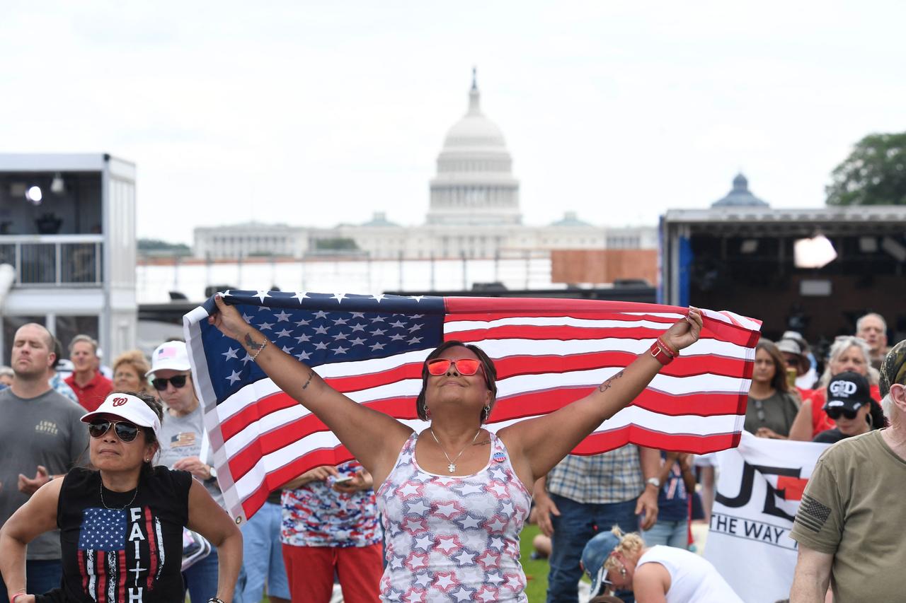 An attendee holds an American flag over her head during "Rededicate 250: A National Jubilee of Prayer, Praise and Thanksgiving" on the National Mall in Washington, DC, on May 17, 2026. (AFP Photos)