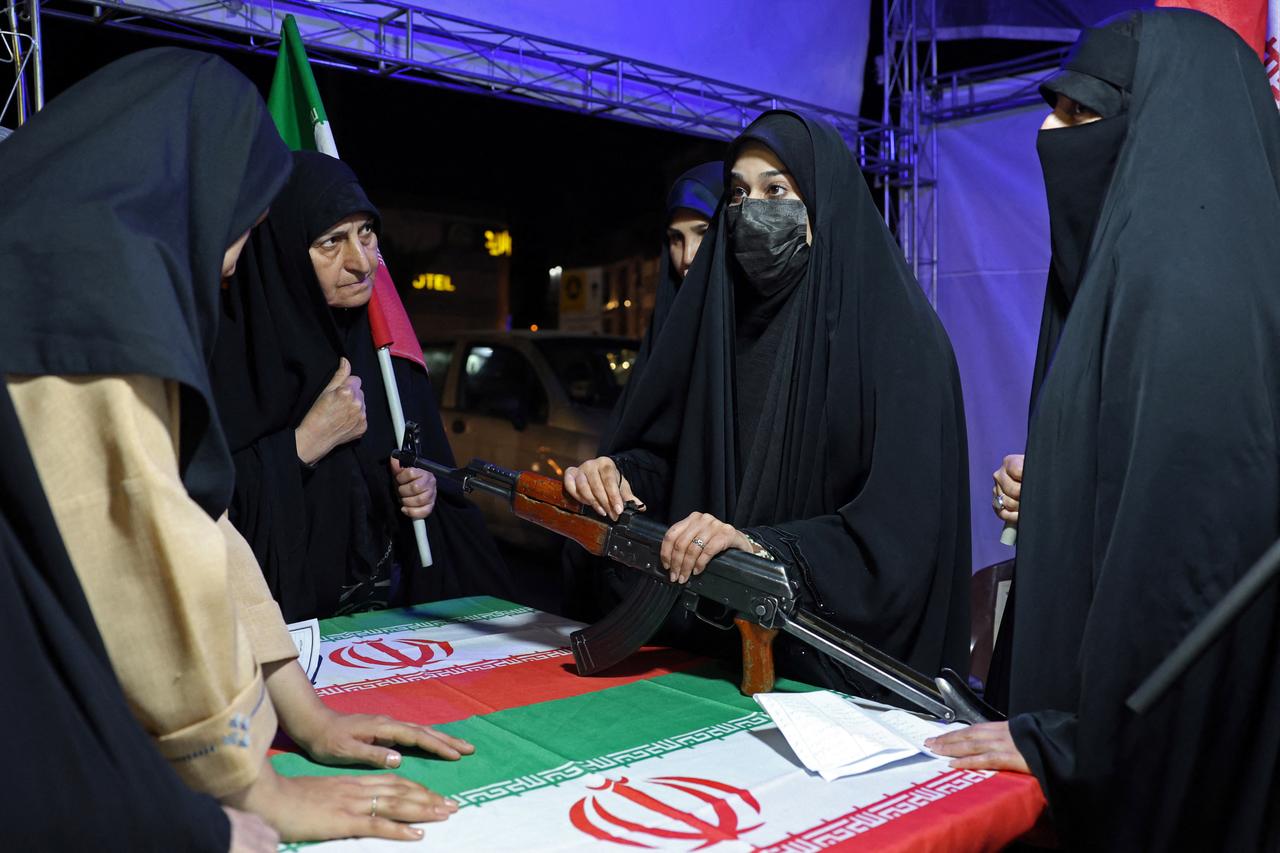 An Iranian military personnel (C) educates women about how to use a gun at a booth in Hafte Tir Square, in Tehran on May 17, 2026. (AFP Photo)