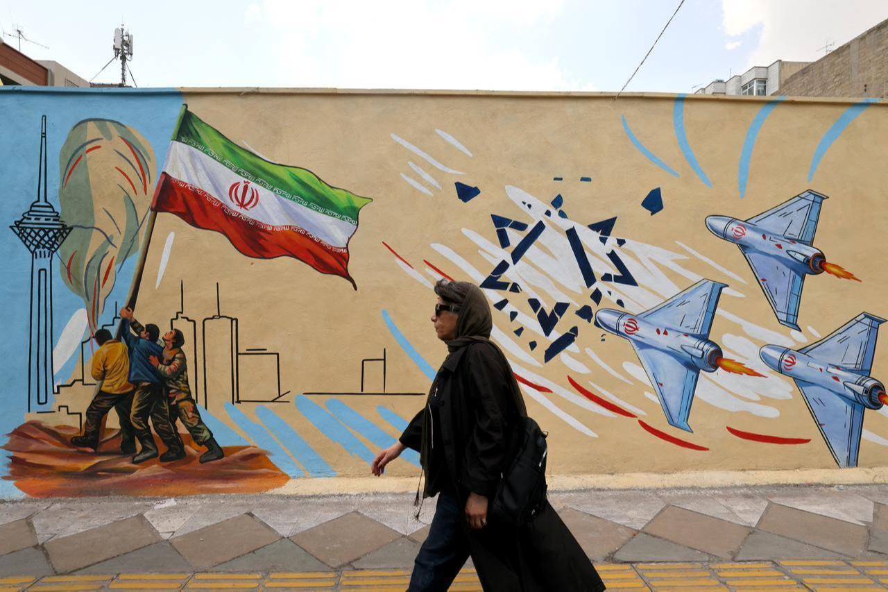 A woman walks past an anti-USA and anti-Israel mural in Tehran on April 21, 2026, amid a ceasefire in the region. (AFP Photo)