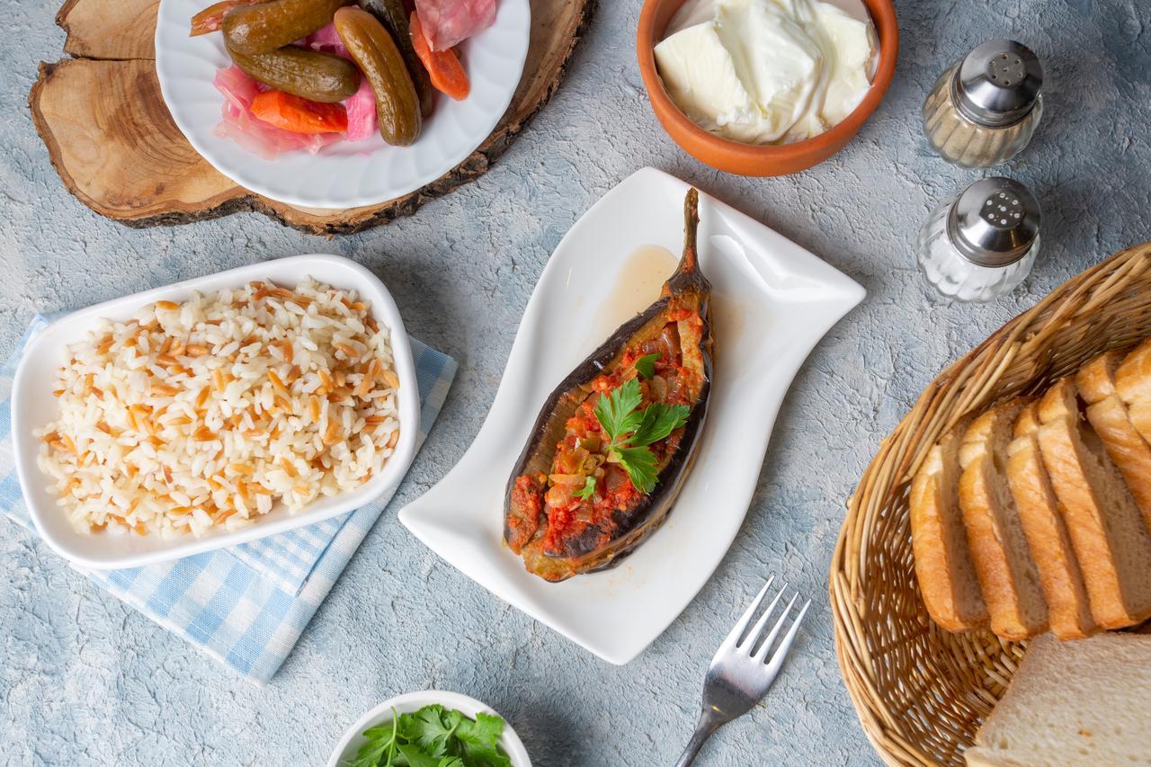 Imam bayildi served at the center of a wider Turkish table, accessed on May 2, 2026. (Adobe Stock Photo)