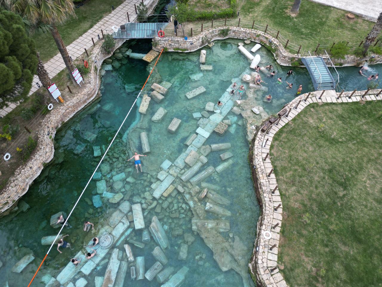 An aerial view shows visitors exploring the Cleopatra Pool, where historical remains lie beneath clear thermal waters in Pamukkale, Denizli, Türkiye. (AA Photo)