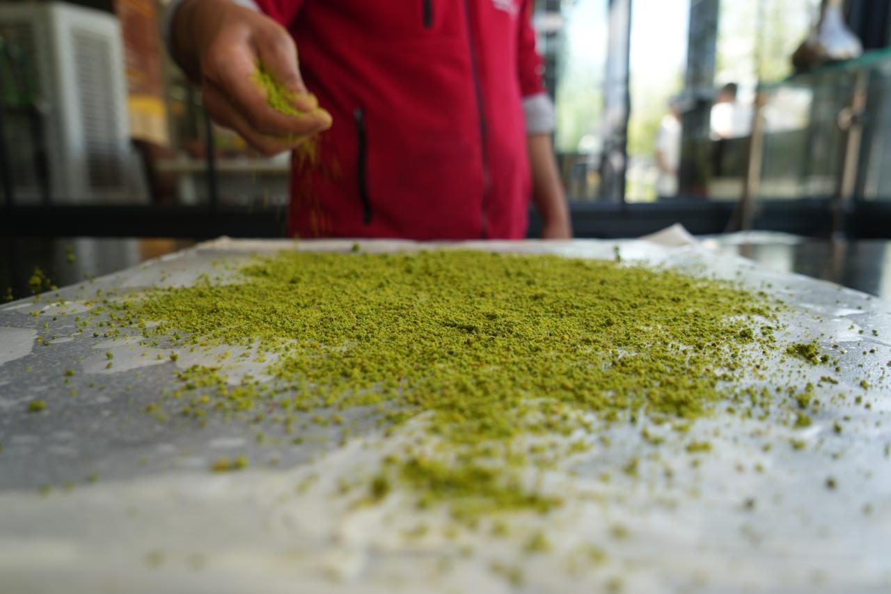 Artisan scattering ground Antep pistachios over paper-thin dough to prepare Gaziantep’s traditional katmer.
(IHA Photo)