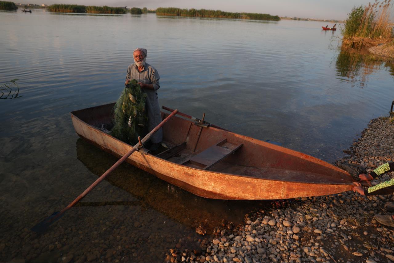 Fisherman Yusuf Habash stands in metal boat at the edge of the Euphrates River in Raqqa, Syria, May 20, 2026. (AA Photo)