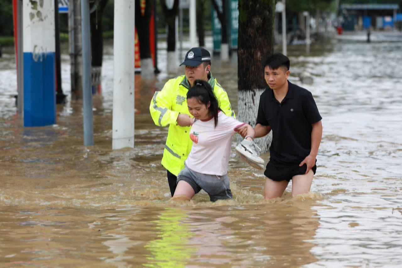 Police officer assists woman navigate submerged street in Duyun, Guizhou, southwestern China, May 19, 2026. (AFP Photo)