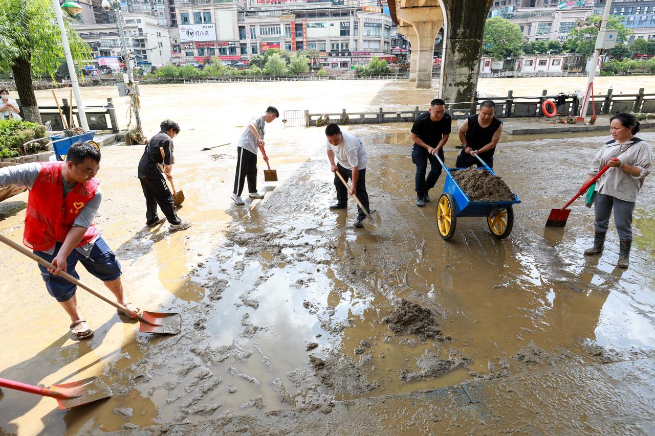 People clean up mud along submerged road in Duyun, Guizhou , southwestern China, May 19, 2026. (AFP Photo)
