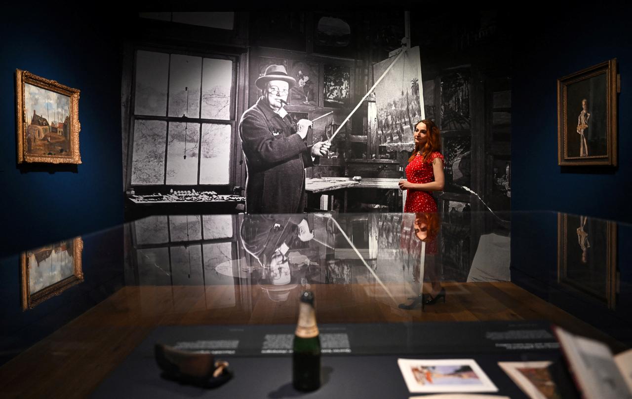 A gallery assistant poses for a photograph (C) by photographer Hans Wild at the "Winston Churchill: The Painter" exhibition at the Wallace Collection in London, England, on May 20, 2026. (AFP Photo)