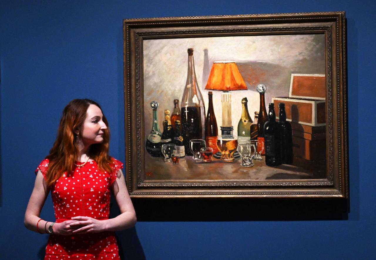 A gallery assistant poses for a photograph by 'Bottlescape 1932' pictured at the "Winston Churchill: The Painter" exhibition at the Wallace Collection in London, England on May 20, 2026. (AFP Photo)