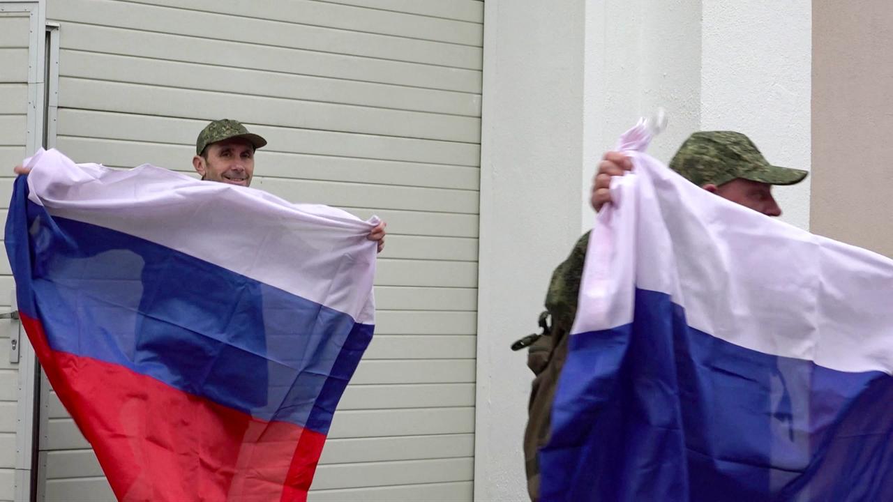 This video grab taken from a handout footage on May 15, 2026, shows Russian prisoners of war (POWs) walking with flags to board a bus following an exchange of prisoners at an undisclosed location in Belarus. (Photo by Handout/Russian Defense Ministry/AFP)