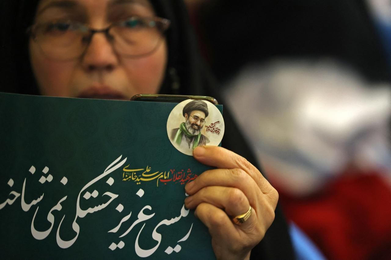 An Iranian woman holds a poster with a small image of the current Iranian supreme leader, Mojtaba Khamenei, during a gathering at the Imam Khomeini Mosque (Mosalla) in Tehran, May 24, 2026. (AFP Photo)
