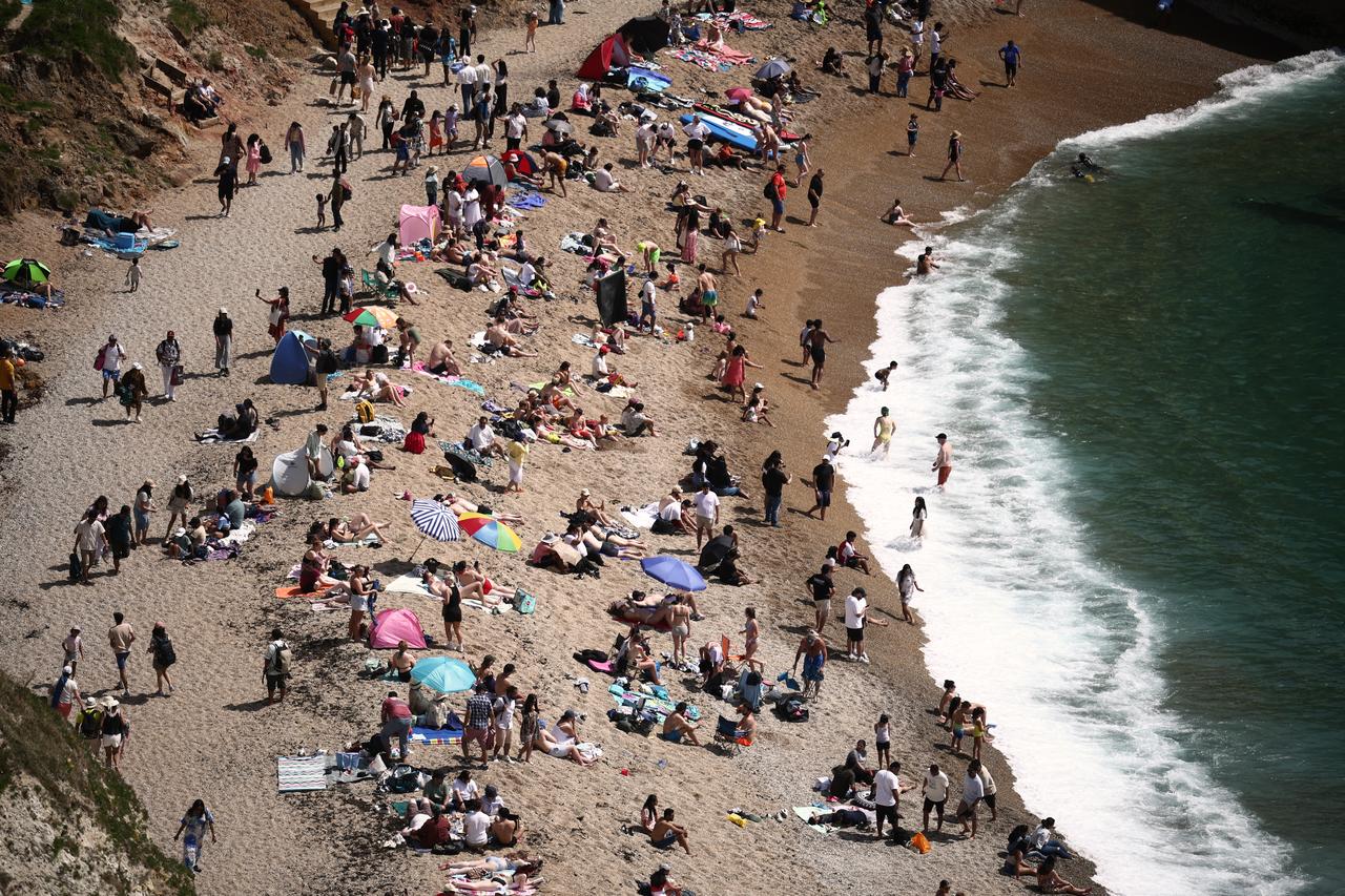 People relax in the sunshine on Durdle Door beach, England on May 23, 2026, (AFP Photo)