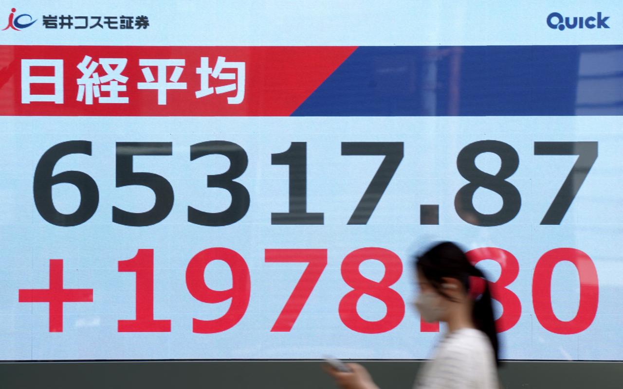 A woman walks past an electronic quotation board displaying the Nikkei Stock Average on the Tokyo Stock Exchange along a street in Tokyo, May 25, 2026. (AFP Photo)