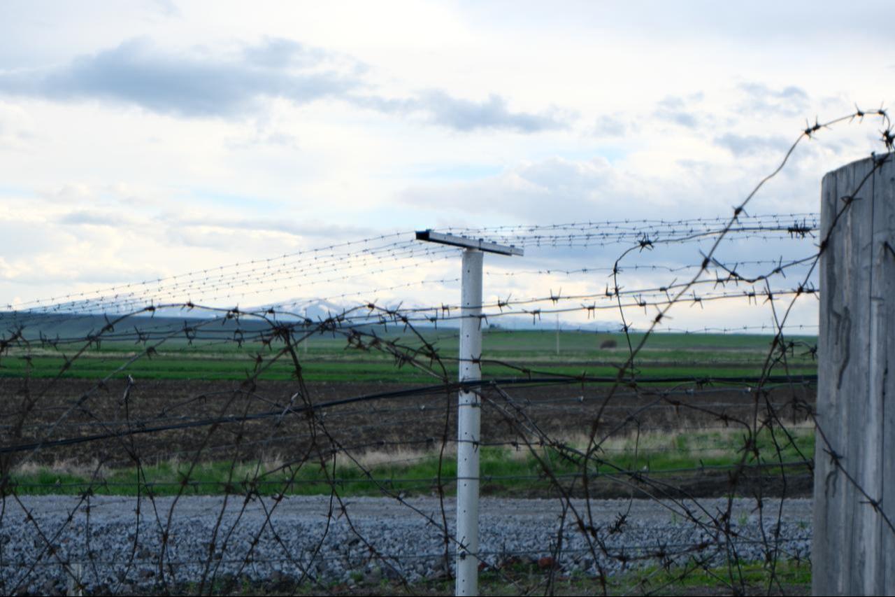 Barbed wire fences line the Akhurik border crossing on the Türkiye-Armenia border, with snow-capped mountains visible in the distance on May 8, 2026. (Yagiz Efe Parmaksiz / Türkiye Today)