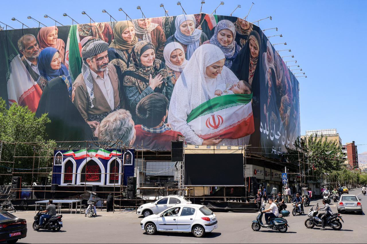 Motorists drive their vehicles near a large political billboard along Enghelab Square in central Tehran, Iran, May 26, 2026. (AFP Photo)