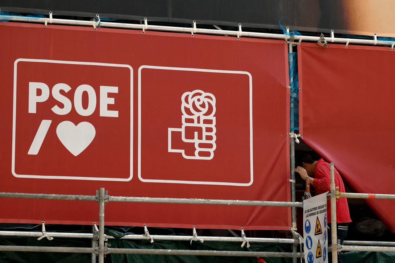 A person passes through a banner deployed on the facade of the ruling Spanish Socialist Party (PSOE) headquarters, where agents from the UCO entered in Madrid, May 27, 2026. (AFP Photo)