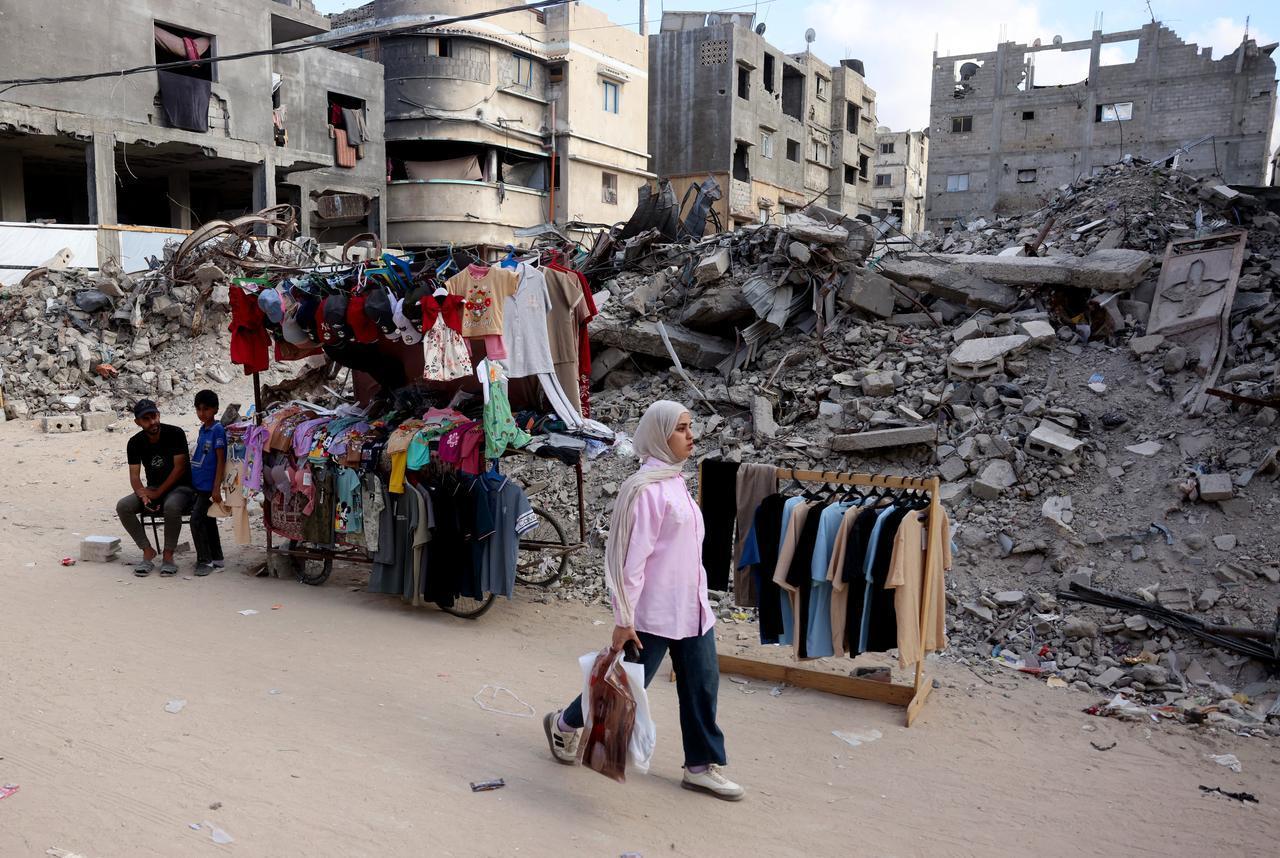 A Palestinian woman walks past a clothes stall set up near the rubble of buildings destroyed in Israeli military strikes, on the eve of the Muslim holiday of Eid al-Adha in Khan Yunis, southern Gaza Strip, May 26, 2026. (AFP Photo)