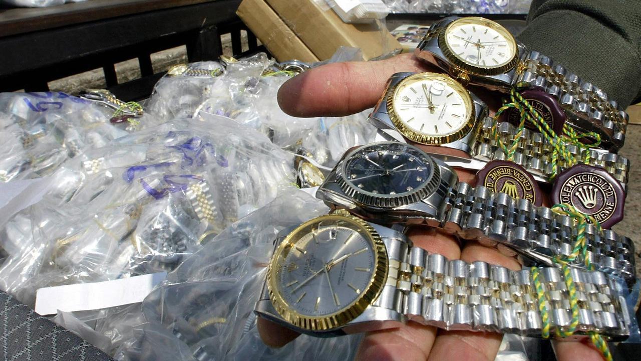 An unidentified Thai customs officer shows counterfeit Rolex watches confiscated in different raids during a display at the customs house in Bangkok, 11 March 2004. (AFP Photo)
