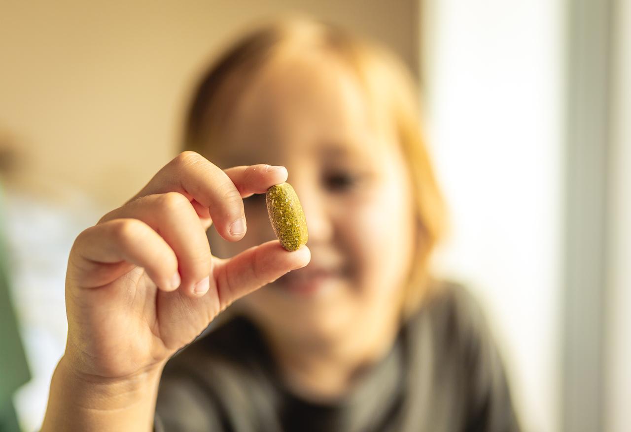 A child holds a pill (Adobe Stock Photo)