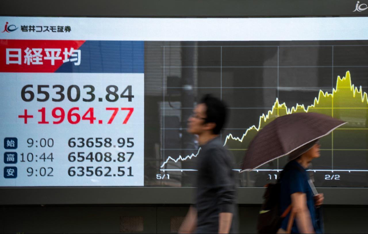 Pedestrians walk past an electronic quotation board displaying the Nikkei Stock Average on the Tokyo Stock Exchange along a street in Tokyo, May 25, 2026. (AFP Photo)