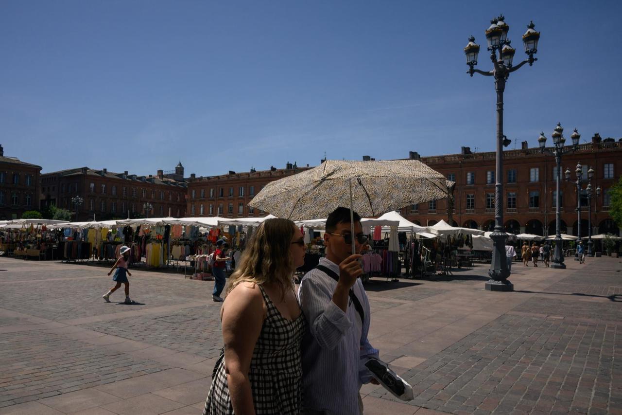 Couple walk beneath an umbrella to protect themselves from the sun in Toulouse, southwestern France, May 27, 2026. (AFP Photo)