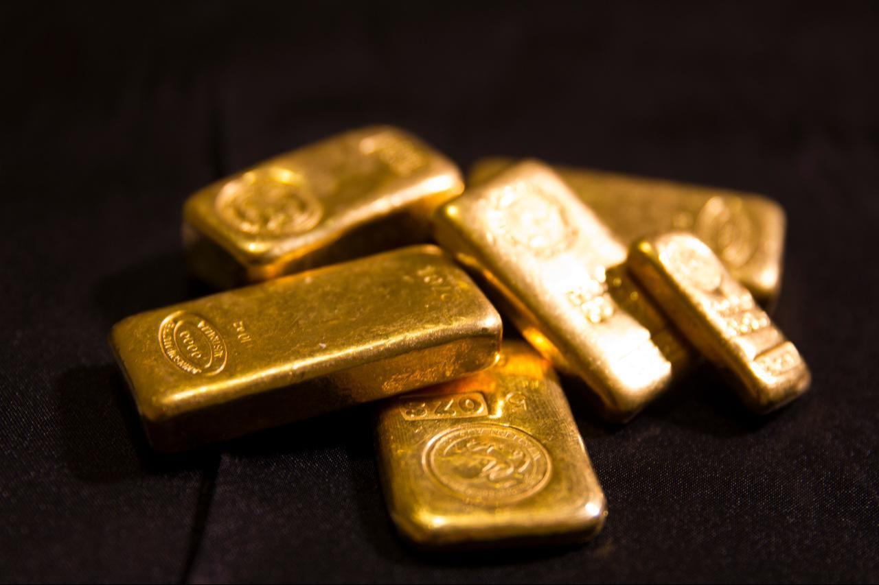 Gold bars are stacked on a dark surface. (Adobe Stock Photo)
