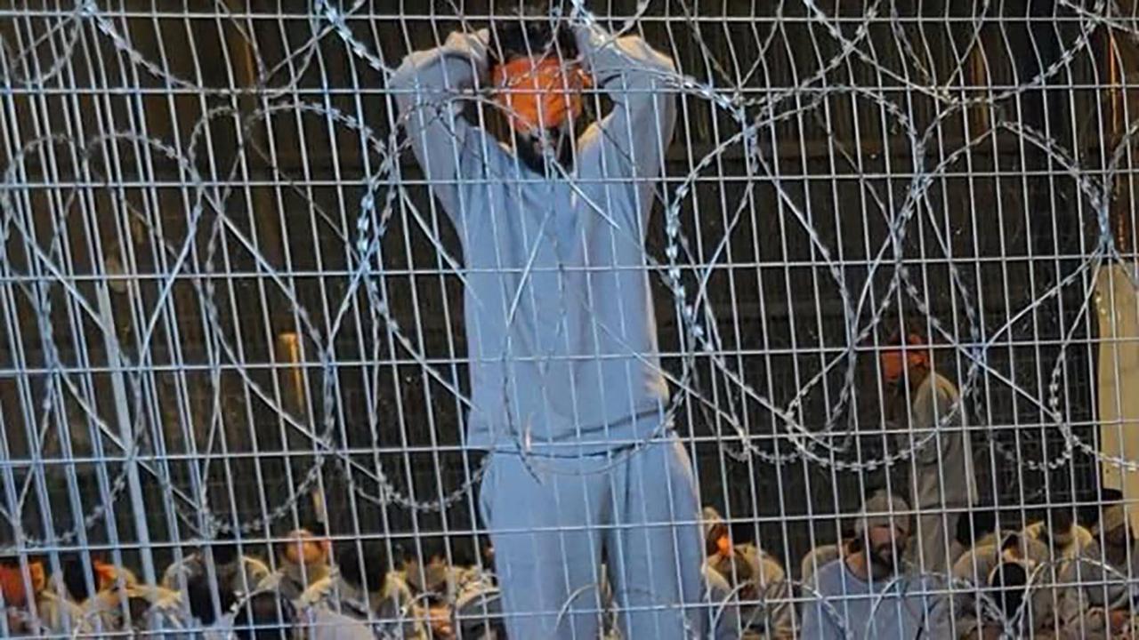A leaked photograph of an enclosure where detainees in gray tracksuits are seen blindfolded and sitting on paper-thin mattresses. (Photo via Channel 12)