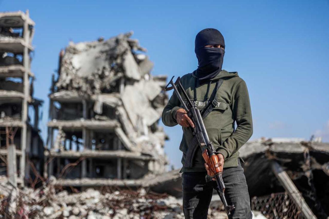 Hamas member stands guard as Egyptian workers, accompanied by members of the International Committee of the Red Cross (ICRC) use a digger as they search for the bodies of hostages in the northern of Gaza Strip, Dec. 1, 2025. (AFP Photo)