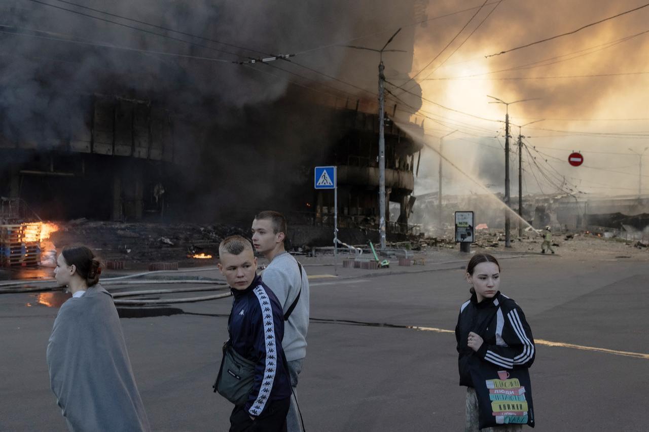 People walk past a shopping building on fire following Russian strikes in Kyiv on May 24, 2026. (AFP Photo)