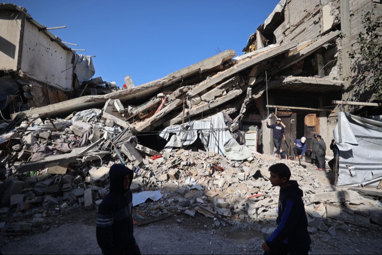 Palestinians walk past the debris of a collapsed house that was previously damaged by an Israeli strike, at the Maghazi refugee camp in the central of Gaza Strip, January 5, 2026. (AFP Photo)