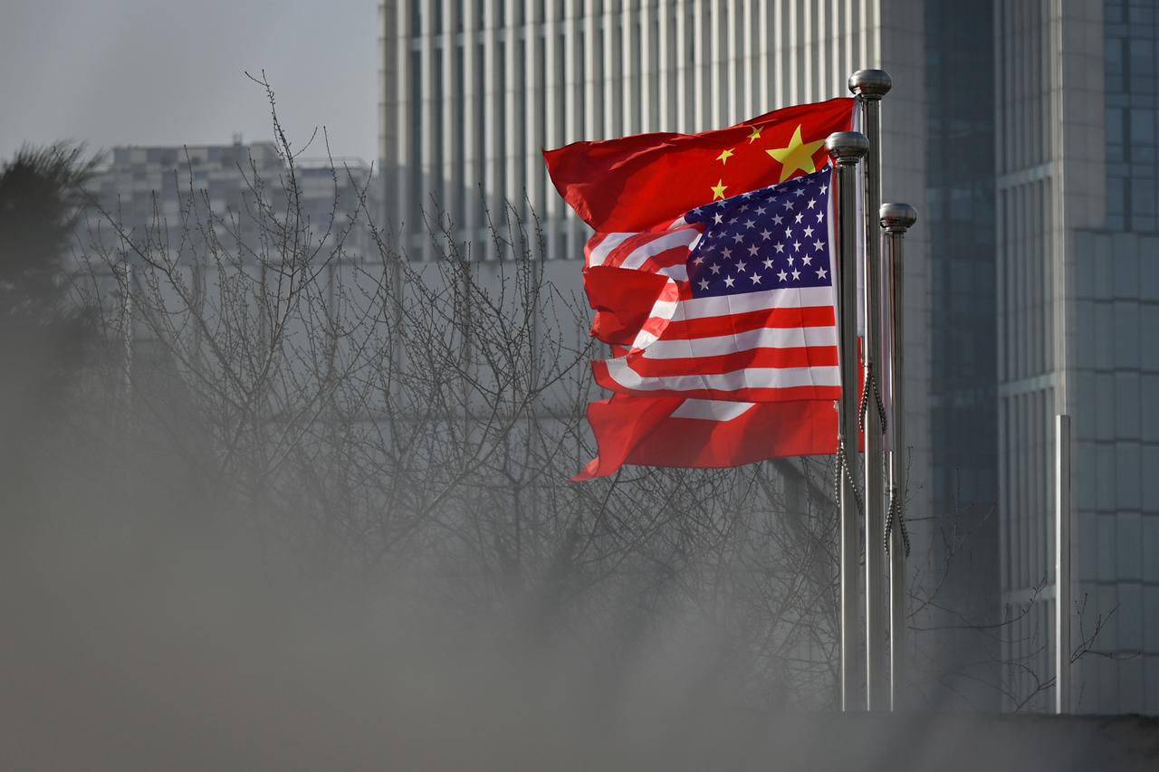 Chinese and US national flags flutter at the entrance of a company office building in Beijing on January 19, 2020. (AFP Photo)