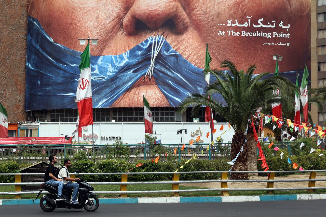 Iranians drive past a billboard featuring US President Donald Trump and the Strait of Hormuz, erected on Valiasr Square in Tehran May 28, 2026. (AFP Photo)