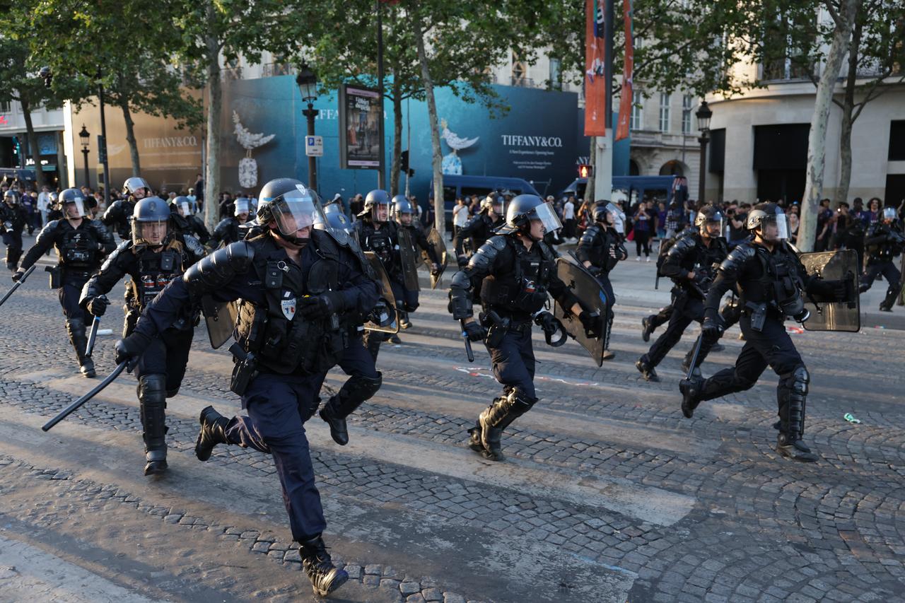 Police officers run to disperse PSG supporters on the Champs-Elysees Avenue, May 30, 2026. (AFP Photo)