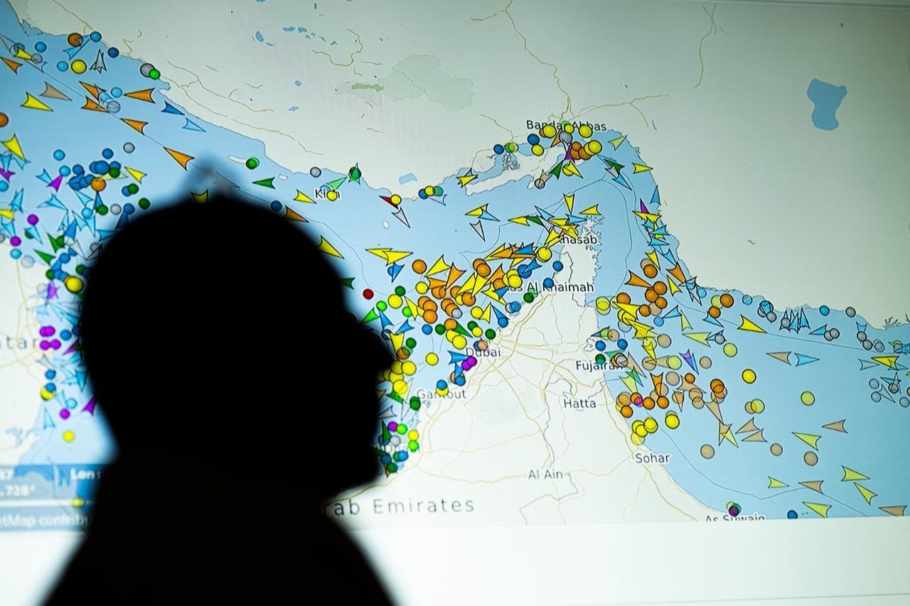 A photo illustration taken in Nicosia on May 4, 2026, shows a person in front of a large screen displaying vessel movements in the Strait of Hormuz on a ship-tracking website. (AFP Photo)