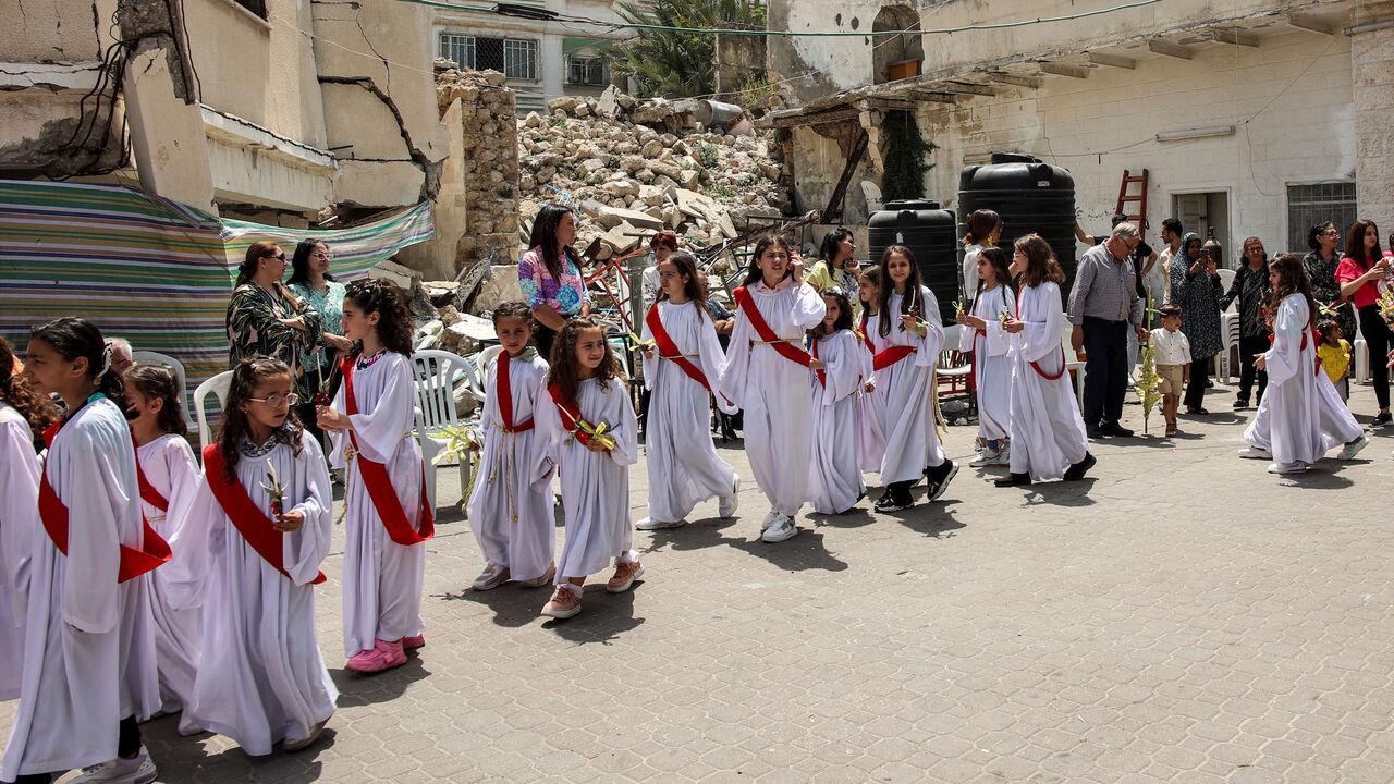 Child deaconesses walk past the rubble of a collapsed building in a procession during the Palm Sunday service outside the Greek Orthodox Church of St Porphyrius (Porphyrios) in Gaza City, April 28, 2024. (AFP Photo)