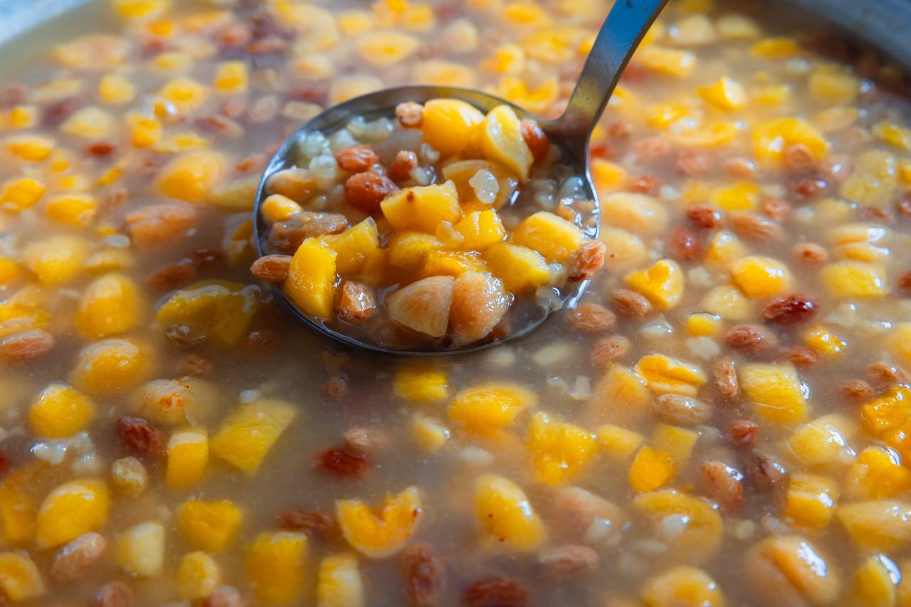 A ladle scoops asure, or Noah's pudding, with grains and dried fruit from a large pot, accessed on May 8, 2026. (Adobe Stock Photo)