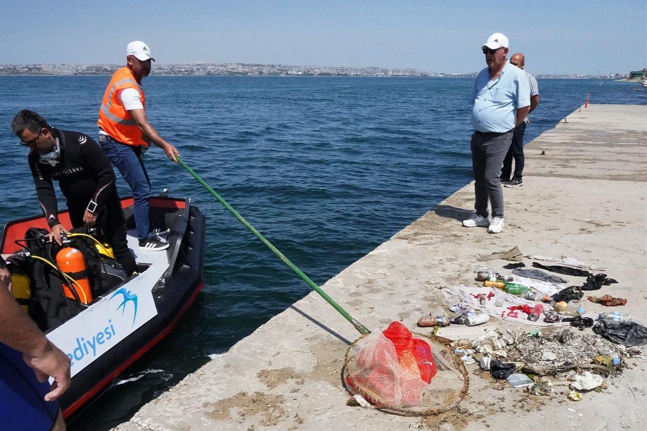 Divers and municipal workers display waste removed from the sea during a clean-up operation in Türkiye. (IHA Photo)