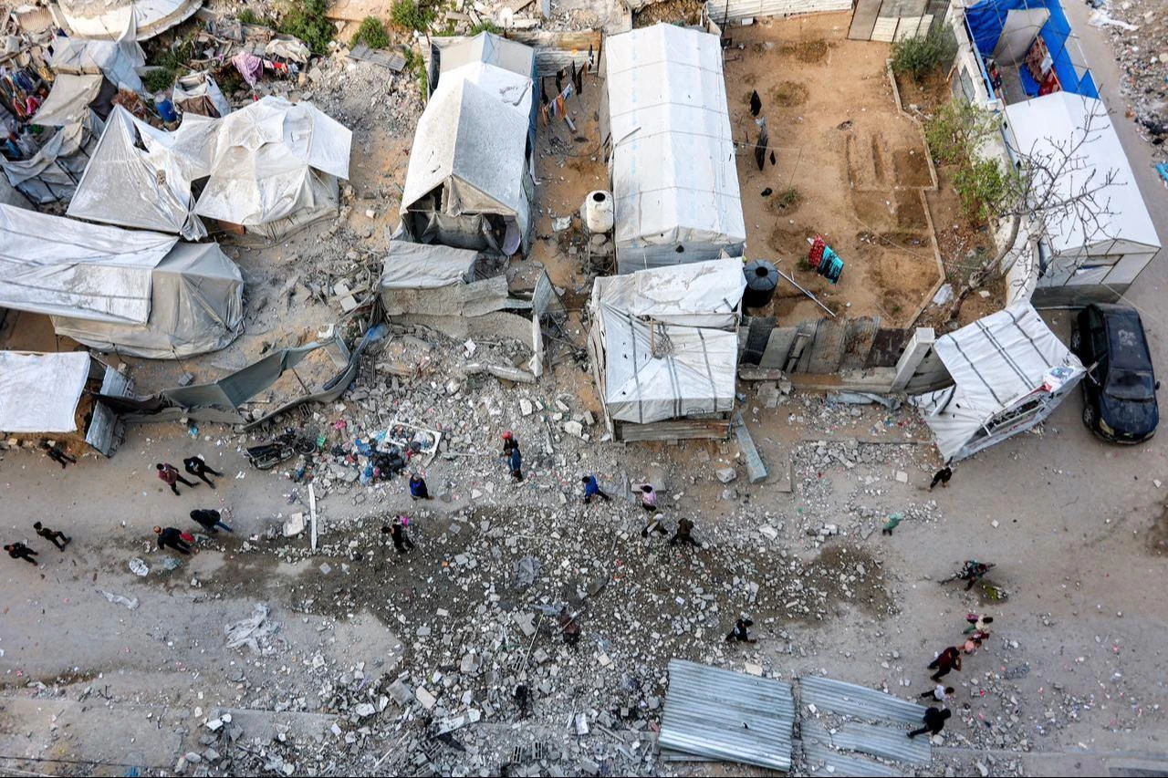 People walk past tents for the displaced outside a residential building that was hit by an Israeli strike the previous day in the Rimal neighbourhood of Gaza City, May 16, 2026. (AFP Photo)