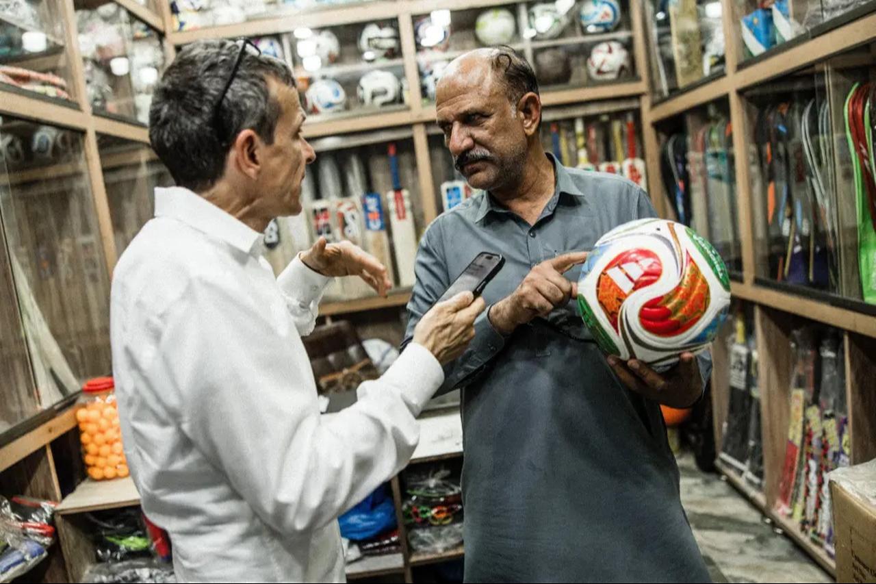 Two men in a sports equipment shop discuss a football. (Photo via Stefan Bohrer/SWNS)