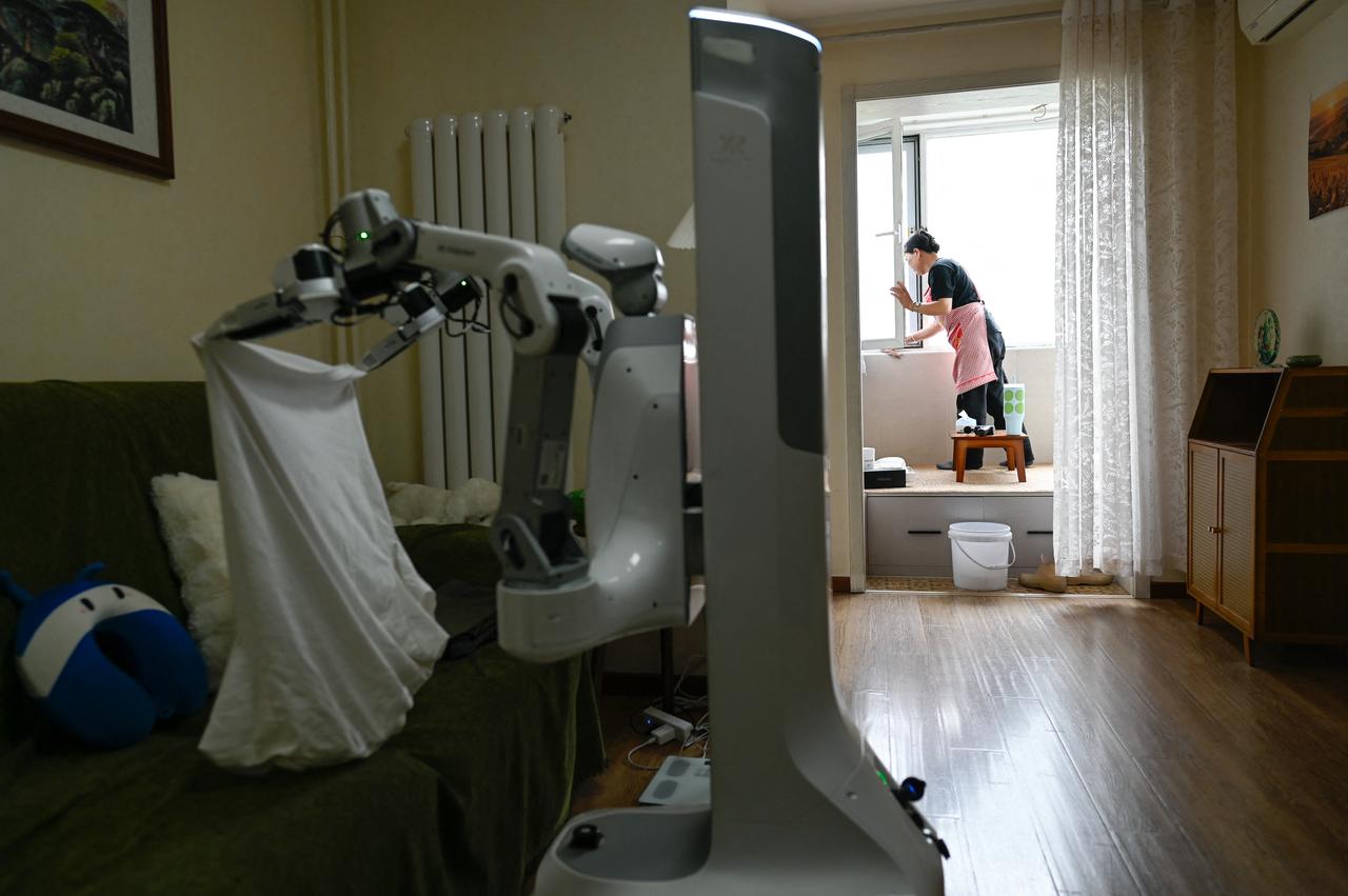 Housekeeper working alongside an X Square Robot at a customer's home in Beijing. (AFP Photo)