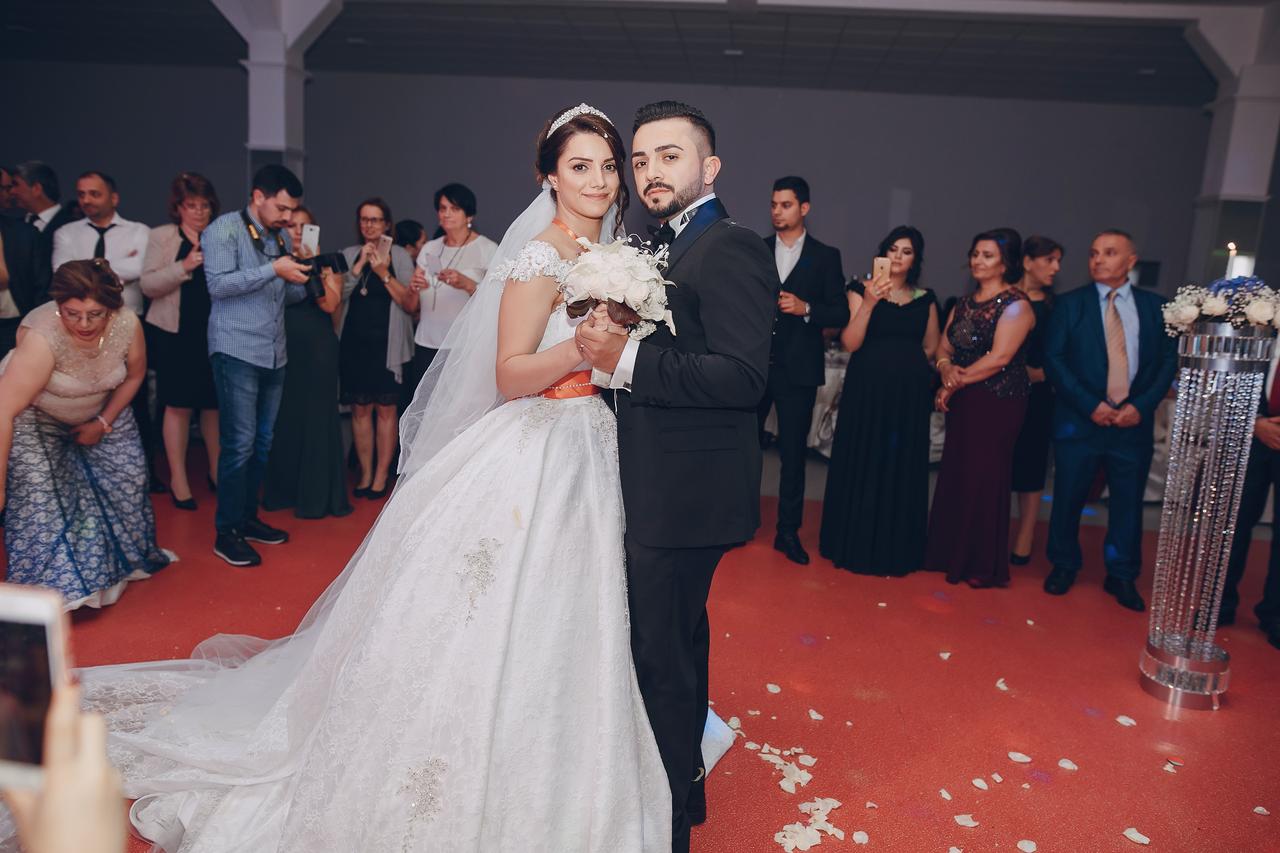A bride and groom pose during a wedding ceremony as guests look on, Türkiye. (Adobe Stock Photo)