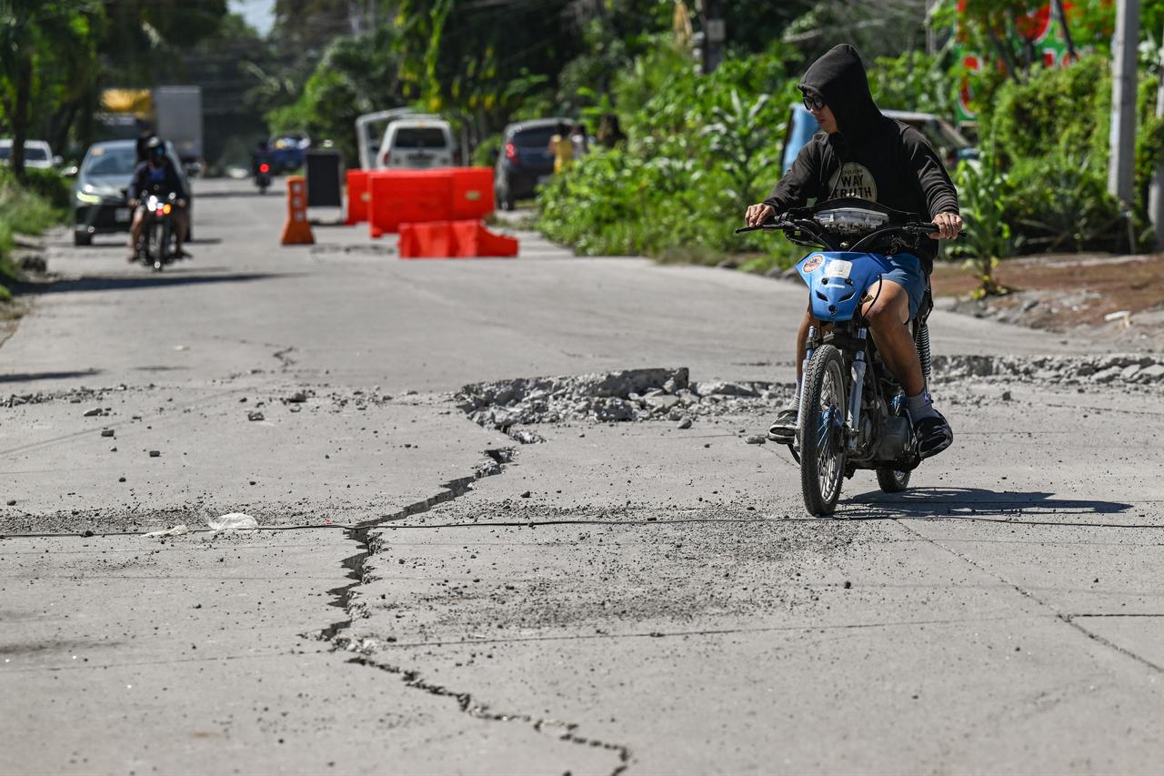 A man rides along a damaged road after a 7.8 magnitude earthquake in General Santos City, June 9, 2026. (AFP Photo)
