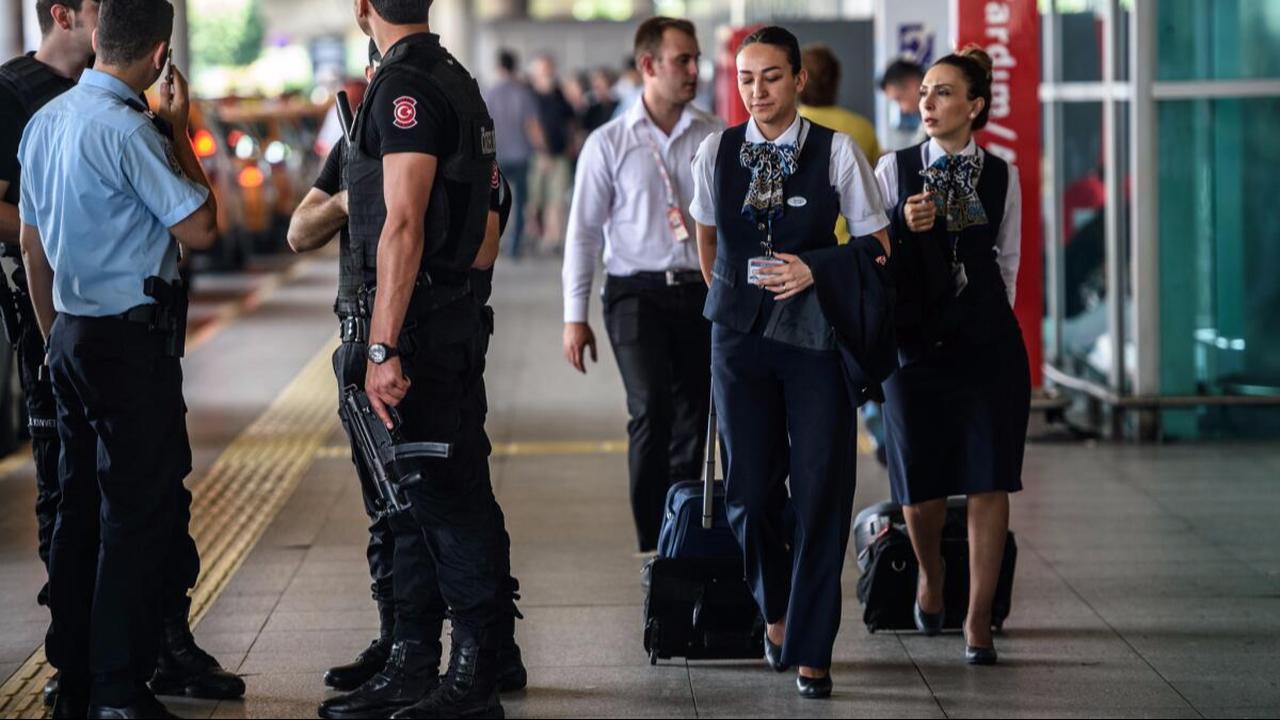 Turkish police officers stand guard as flight attendants walk by at Ataturk Airport in Istanbul, Türkiye, July 1, 2016. (AFP Photo)
