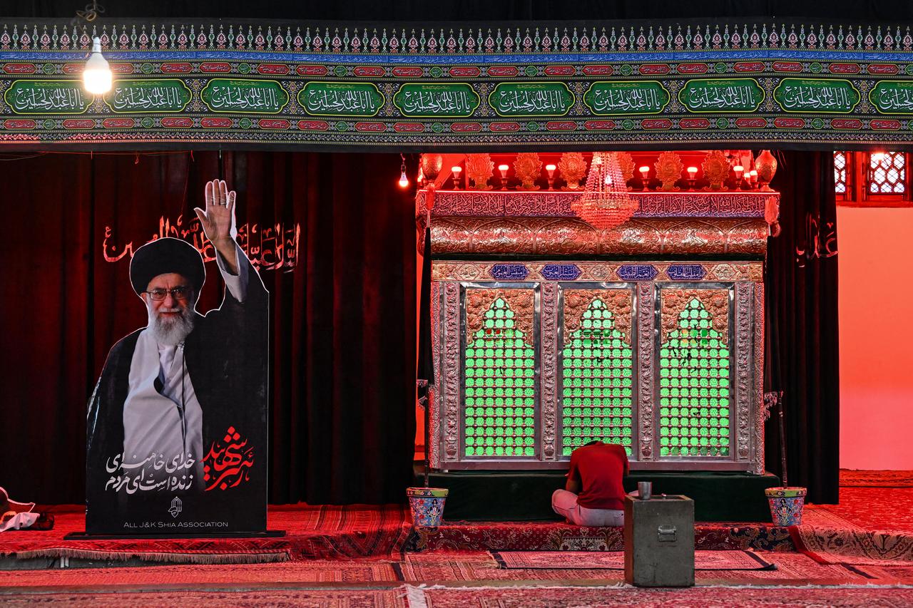 A Kashmiri Shia Muslim prays next to a portrait of Iran's late supreme leader Ayatollah Ali Khamenei inside Imambara Zadibal in Srinagar on June 15, 2026 ahead of the Islamic holy month of Muharram. (AFP Photo)
