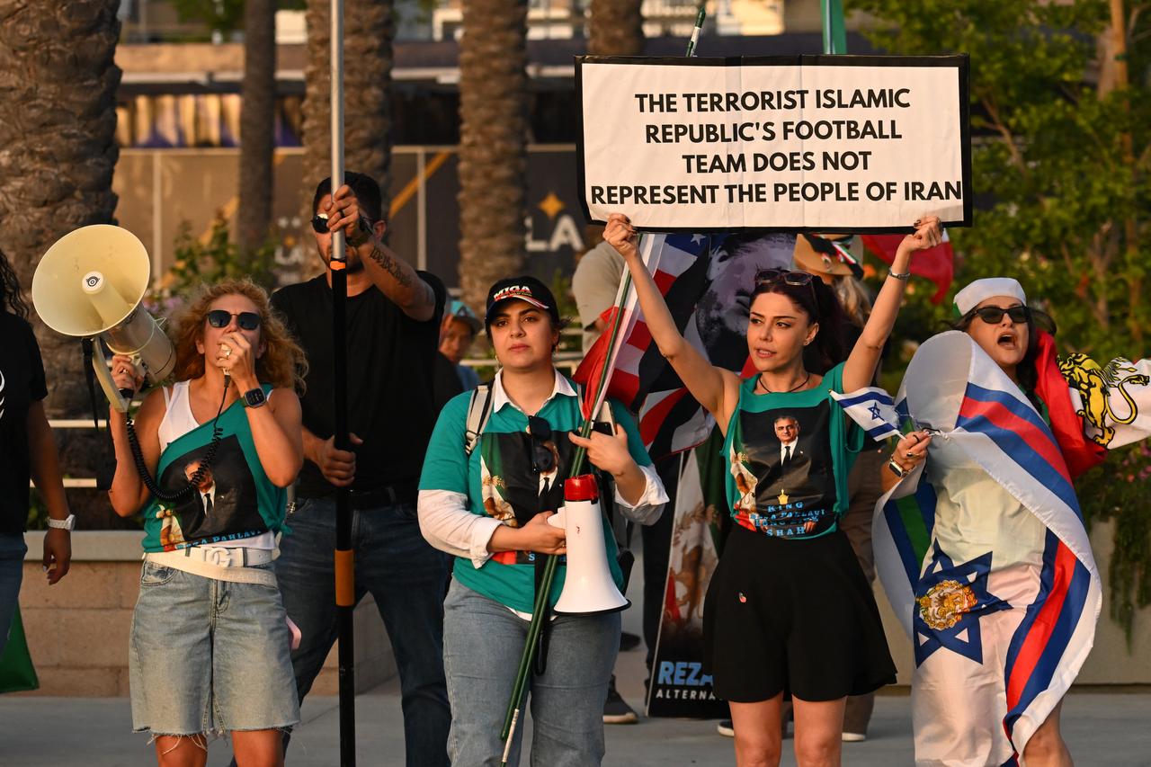 People hold pre-revolutionary Iranian flags as they protest the Iranian regime outside Carson Sports Park before Iran’s training session in Los Angeles on June 14, 2026. (AFP Photo)