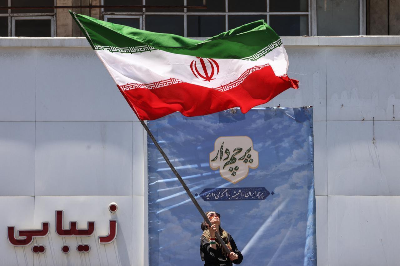 An Iranian woman waves a national flag at Valiasr Square in Tehran on June 15, 2026. (AFP Photo)