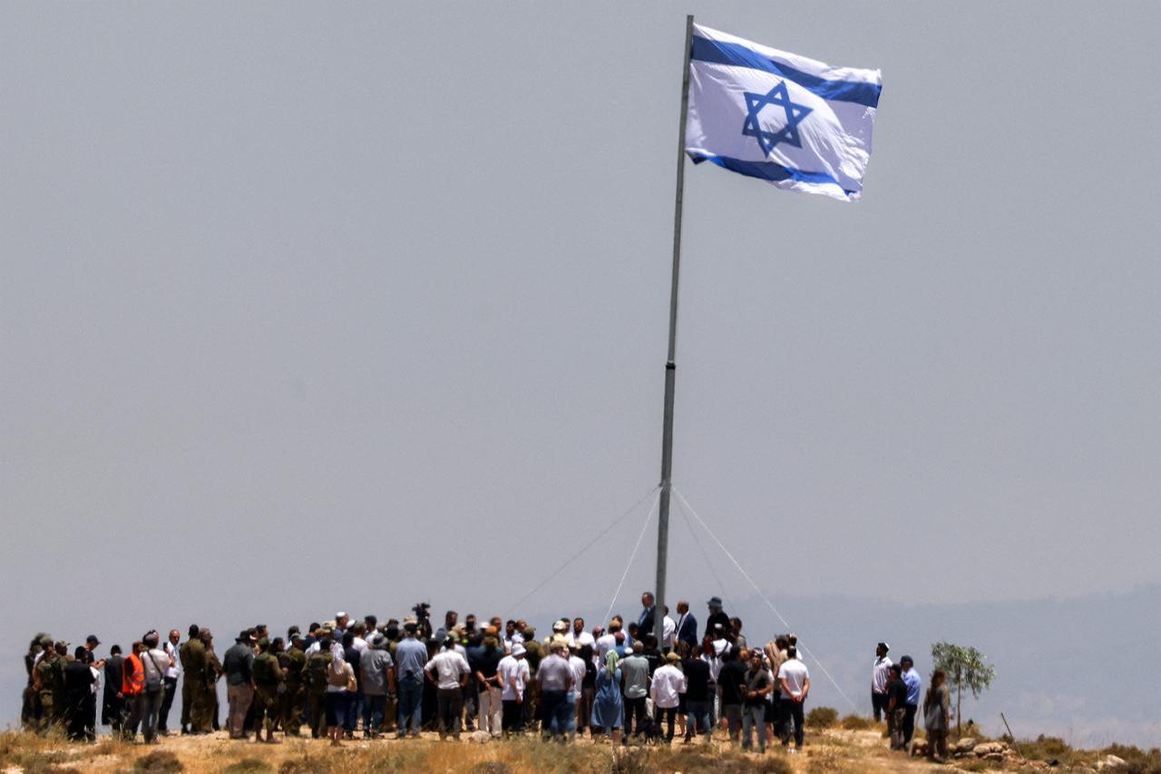 Israeli settlers, accompanied by Israel's far-right finance minister Bezalel Smotrich, raise a large Israeli flag in the occupied West Bank, June 16, 2026. (AFP Photo)