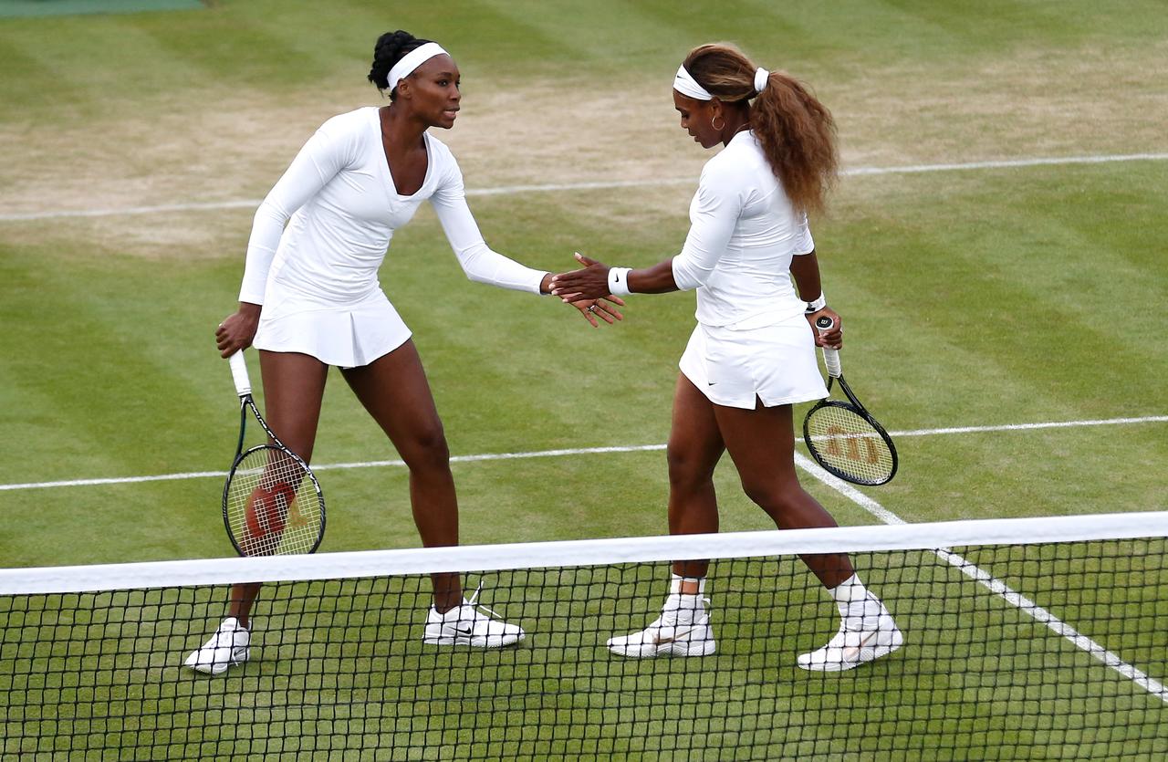 US players Venus Williams (L) and Serena Williams play their women's doubles first round match against Georgia's Oksana Kalashnikova and Ukraine's Olga Savchuk on day three of the 2014 Wimbledon Championships at The All England Tennis Club in Wimbledon, southwest London, England, on June 25, 2014. (AFP Photo)